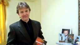 Aleksandr Litvinenko poses with his book, Blowing Up Russia: Terror From Within, at his home in London in May 2002.