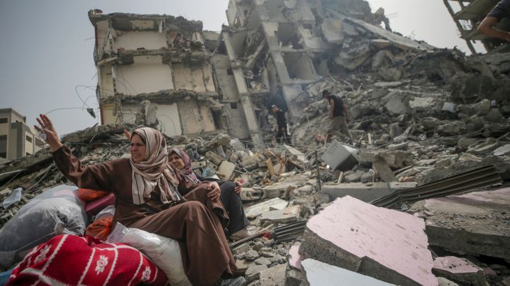 Palestinian women sit among the rubble of a house after returning to Al Nusairat refugee camp