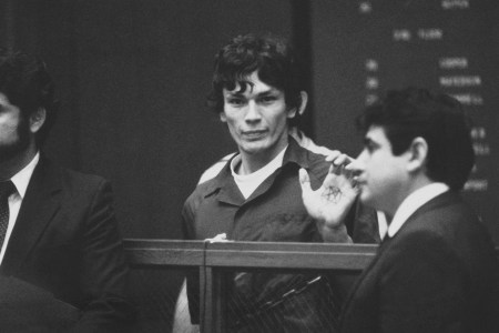 Richard Ramirez, center, know as the Night Stalker shown in custody with pentagram on palm in this undated photo. The man on the right is unidentified. (AP Photo)